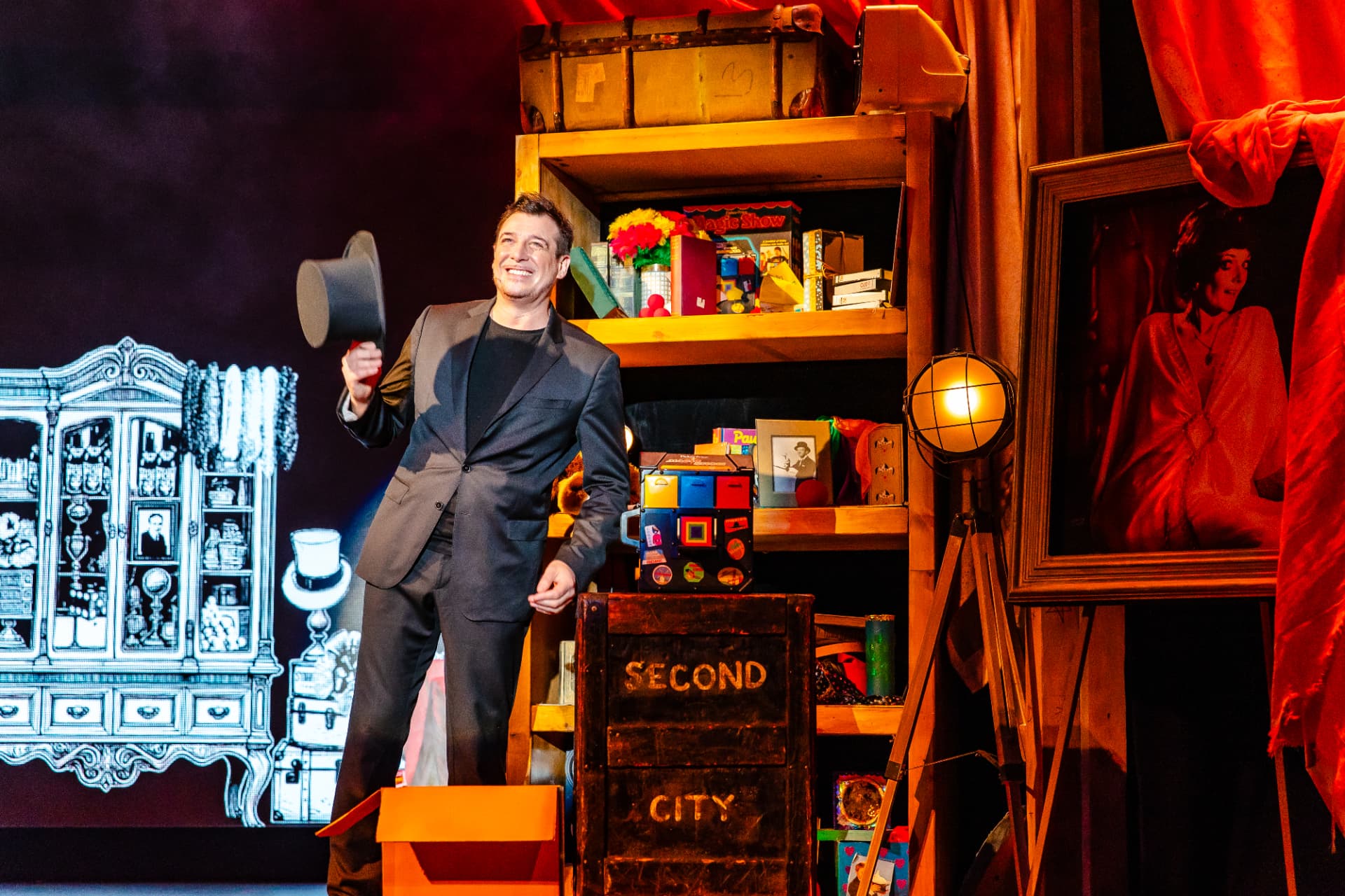 Jamie Allan smiling and holding a top hat on the Amaze stage